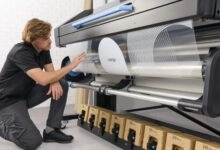 a man kneeling next to a large printer