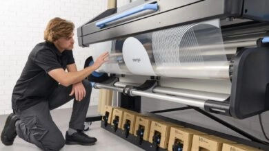 a man kneeling next to a large printer