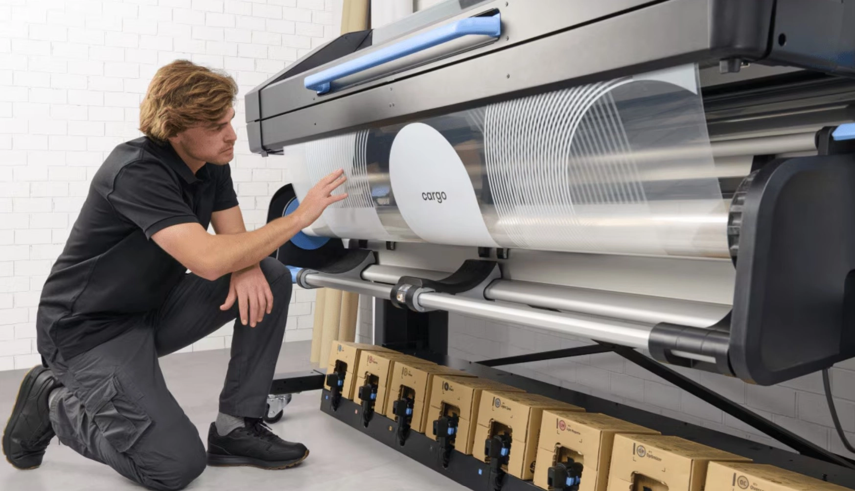 a man kneeling next to a large printer