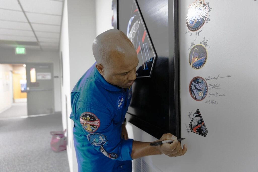 El astronauta Victor Glover firma la insignia de Artemis II en el Centro Espacial Kennedy antes del lanzamiento de la misión lunar tripulada de 10 días a bordo del SLS y la nave Orion.Crédito: NASA/Kim Shiflett